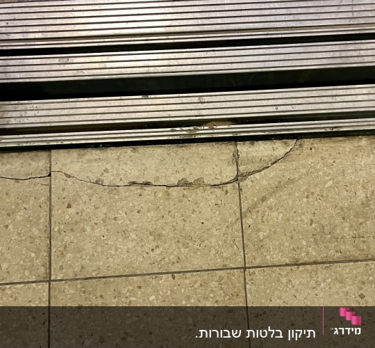 מרצפות רצפה סדוקות ושבורות בצמוד למסילת מתכת לפני תיקון